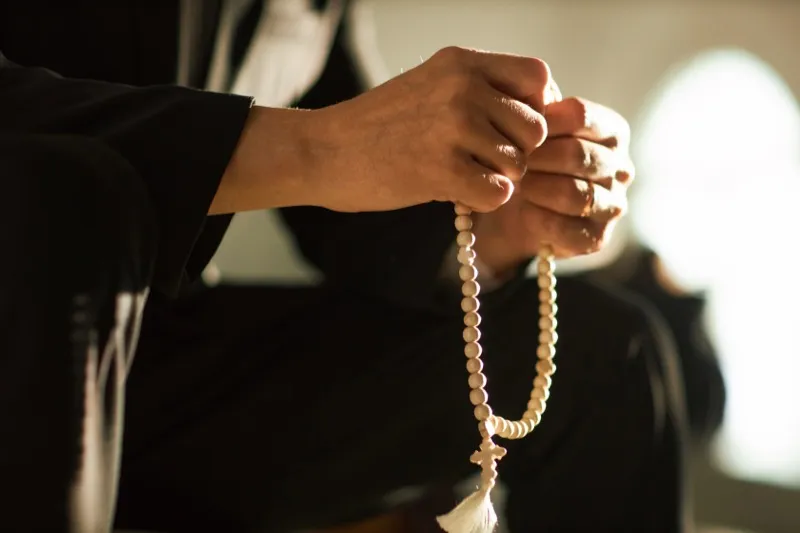 Soft sunlight over hands raised in prayer